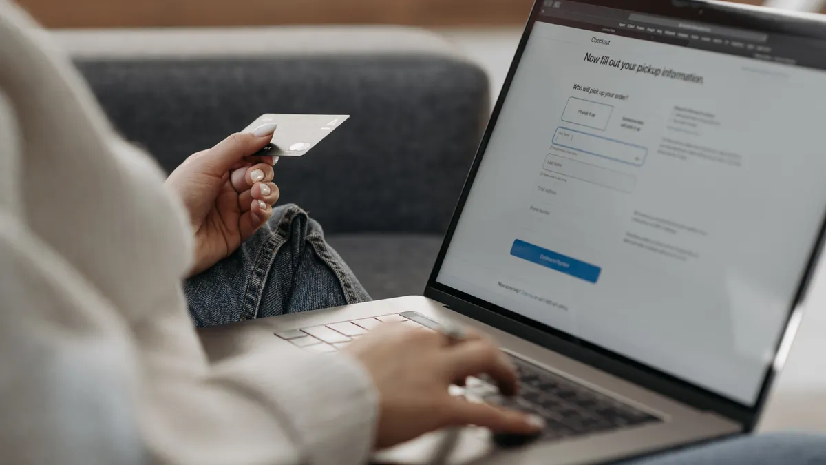 person entering payment details on a laptop with credit card