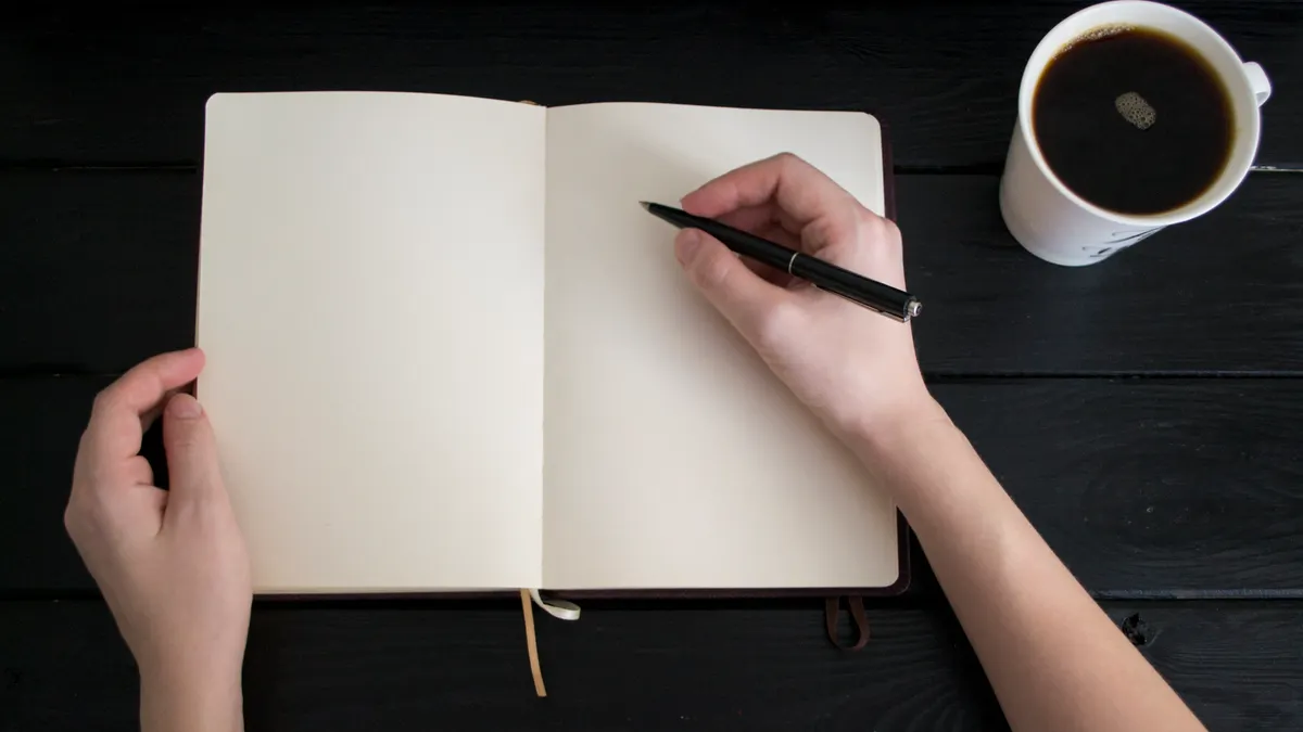 Open notebook being drafted beside coffee