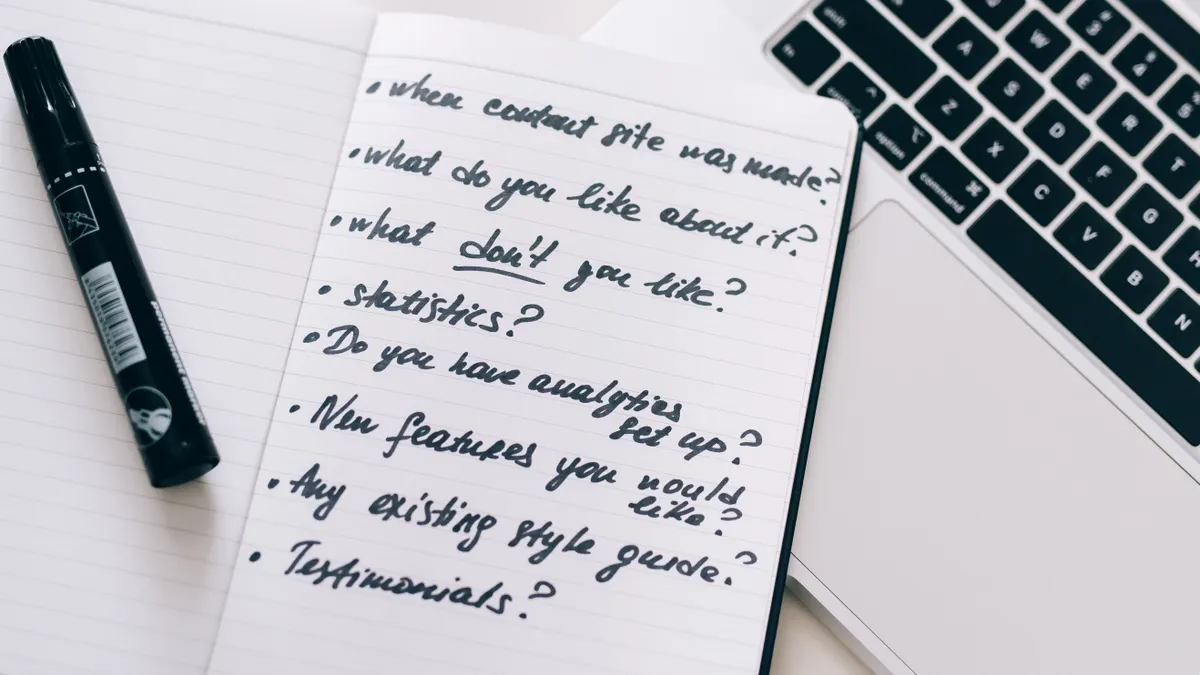 notebook with SEO brief questions beside a laptop